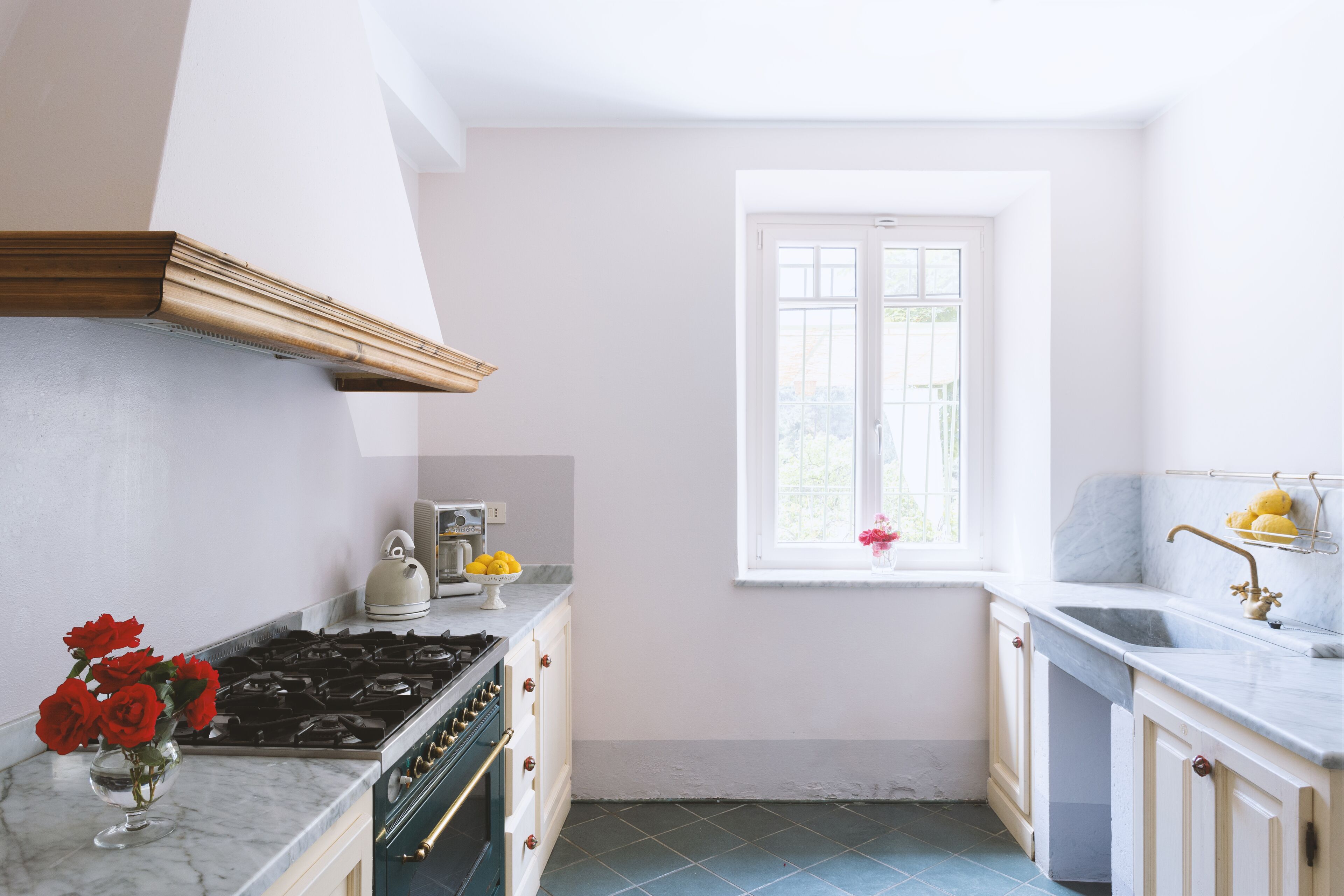 Una cocina con estufa, horno y lavaplatos. Se observa un ventanal con vistas al verdor exterior.