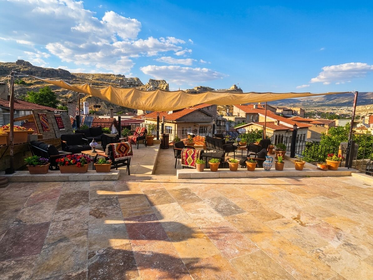 An outdoor seating area with tables and chairs, potted plants, and a view of a mountainous landscape.