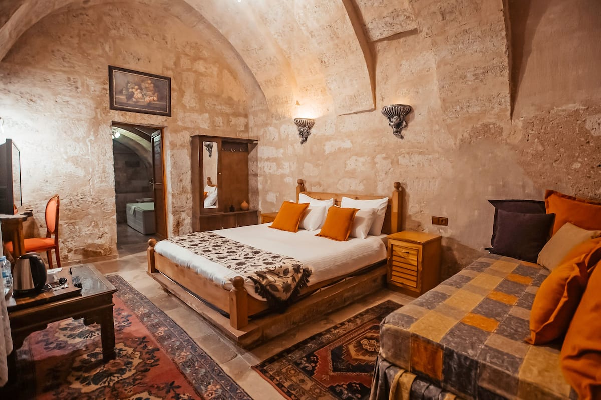 A rustic bedroom with a large bed, wooden furniture, and a stone wall.