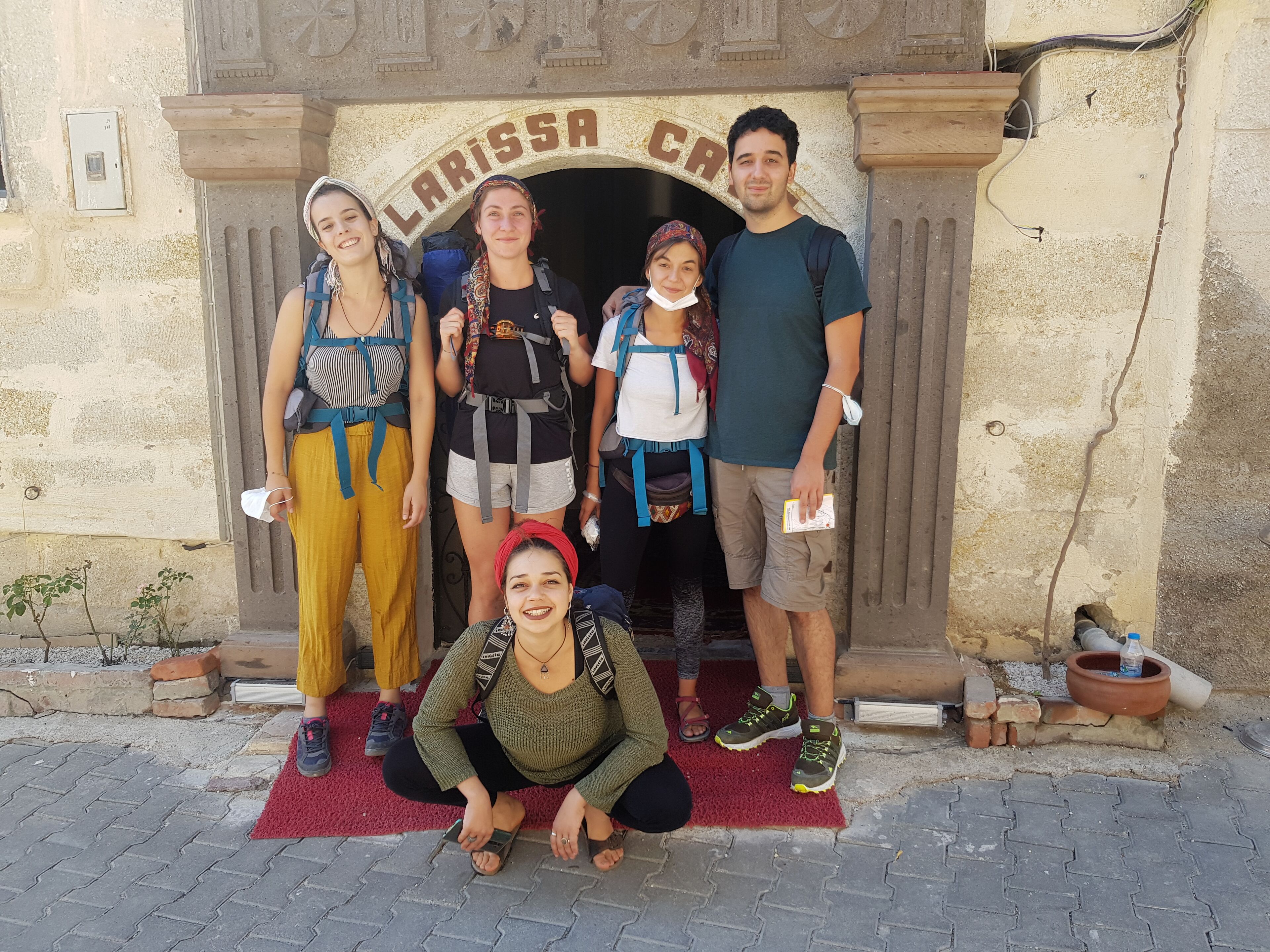 Un grupo de personas frente a un arco de piedra con la inscripción 'LARISSA CRA'.