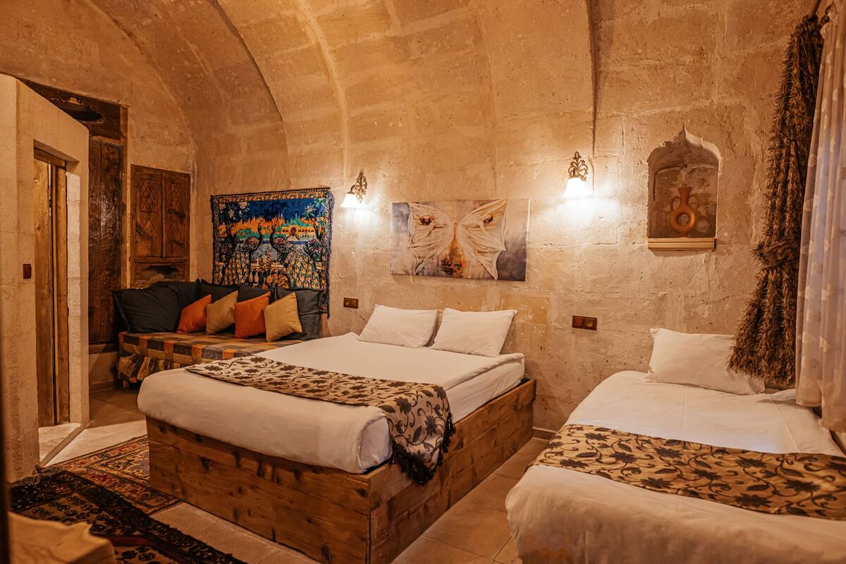 A room with two beds, a wooden headboard, a tapestry, and a wall-mounted light fixture.