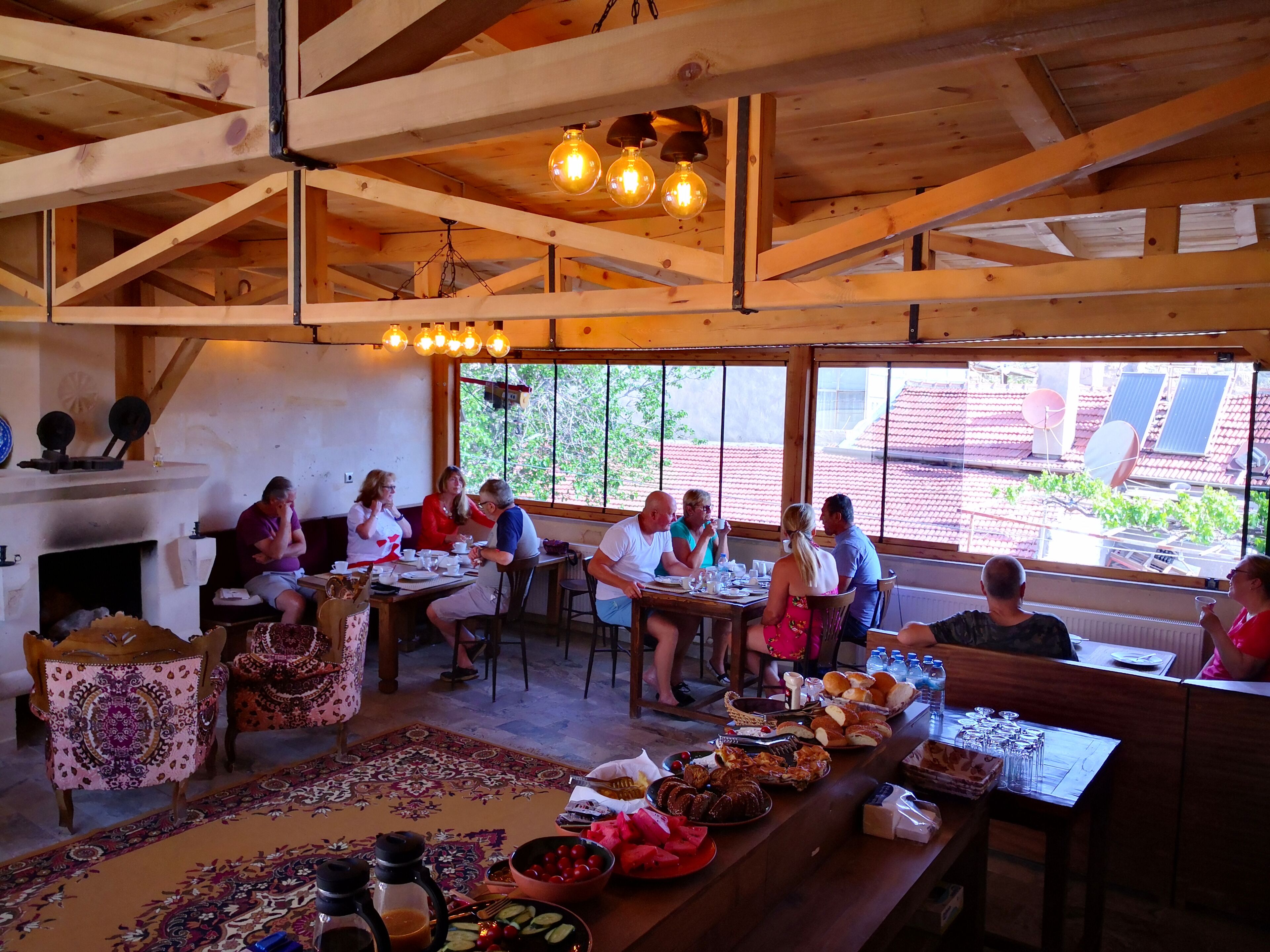 A rustic wooden dining area with a large table set for a meal, surrounded by chairs.