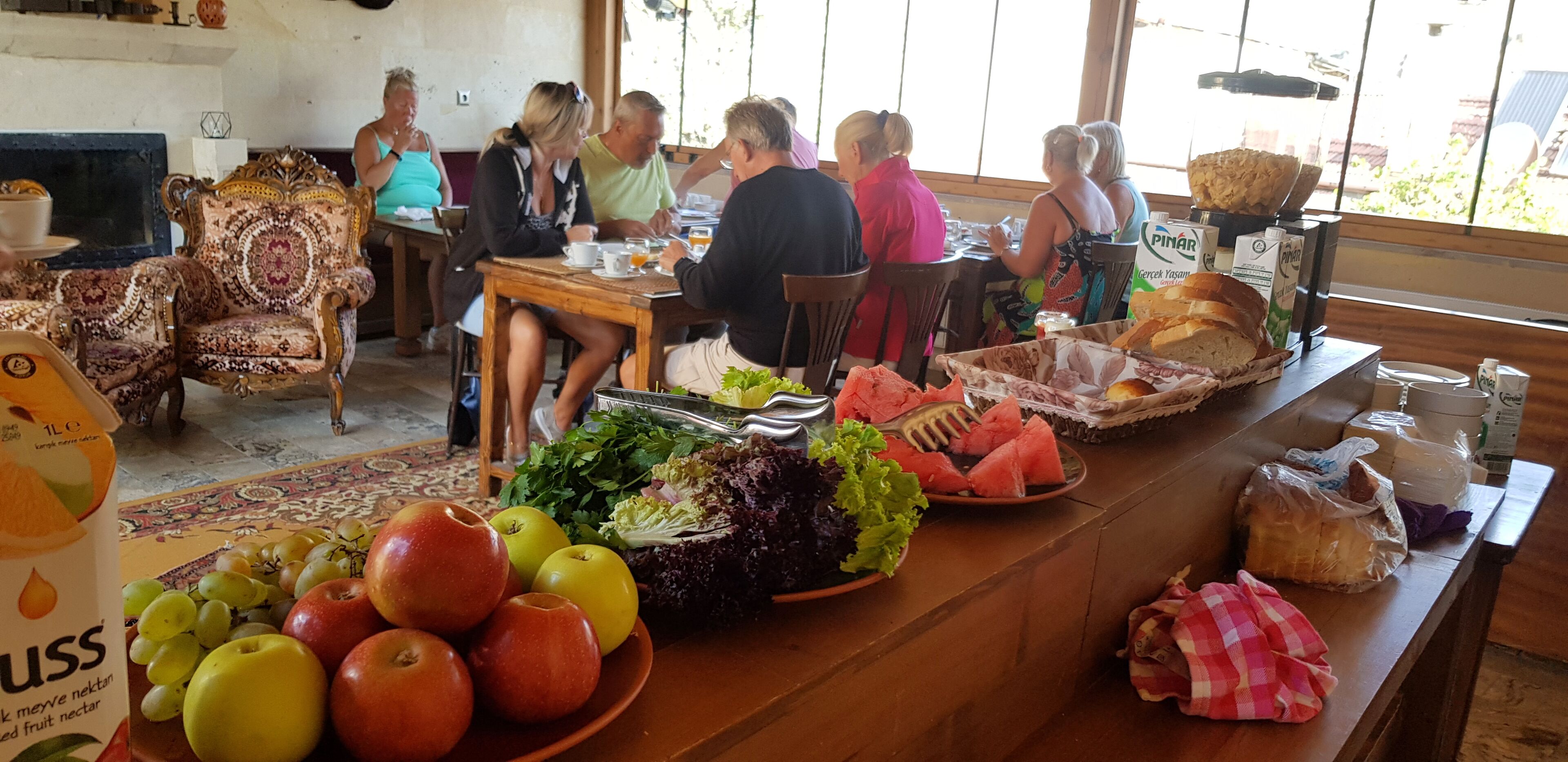 A dining area with a long wooden table, various fruits, vegetables, and bread.