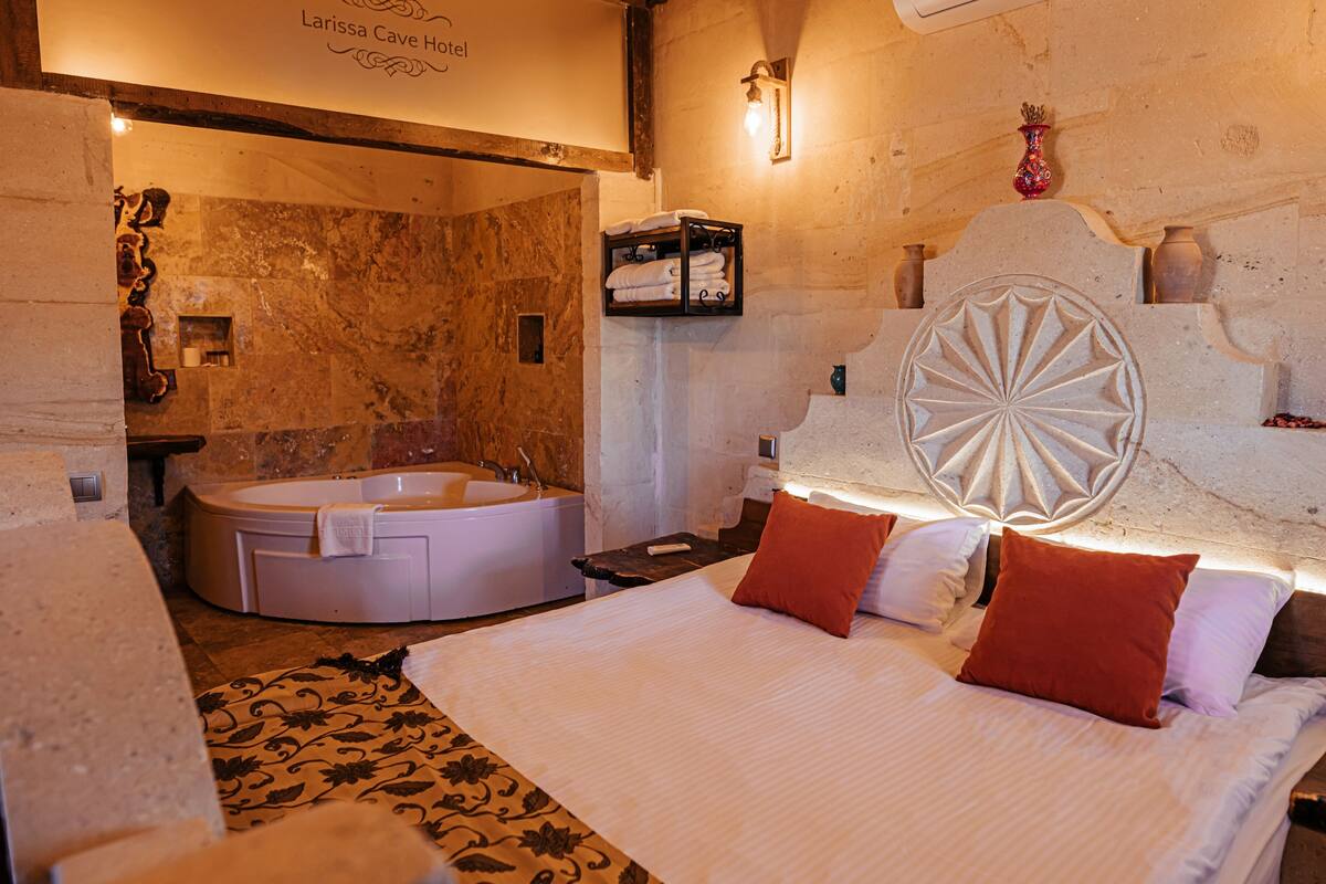 A hotel room with a large bed, a bathtub, and a unique wall design.