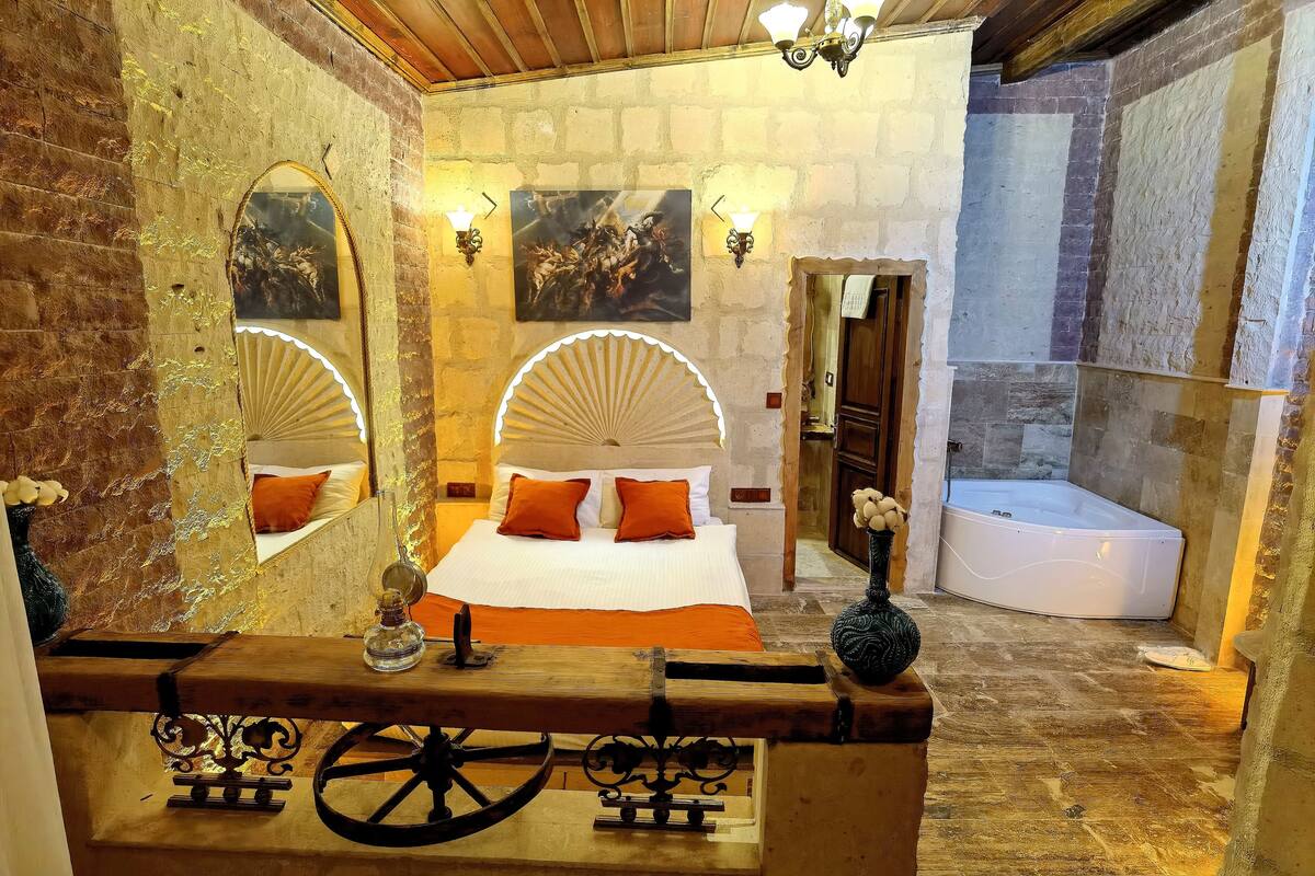 A room with a bed, a wooden table, a mirror, and a bathtub.