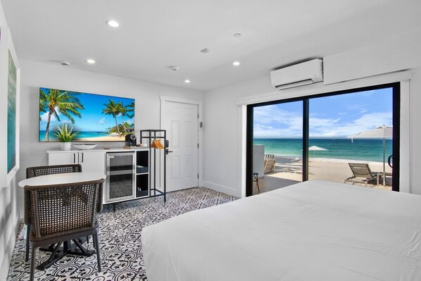 A hotel room with a bed, a desk with a computer, a chair, and a view of the beach. - Seaside at Anna Maria Island Inn (Bradenton Beach)