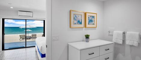 A hotel room with a bed, a white dresser, a small plant, and two framed pictures on the wall.
