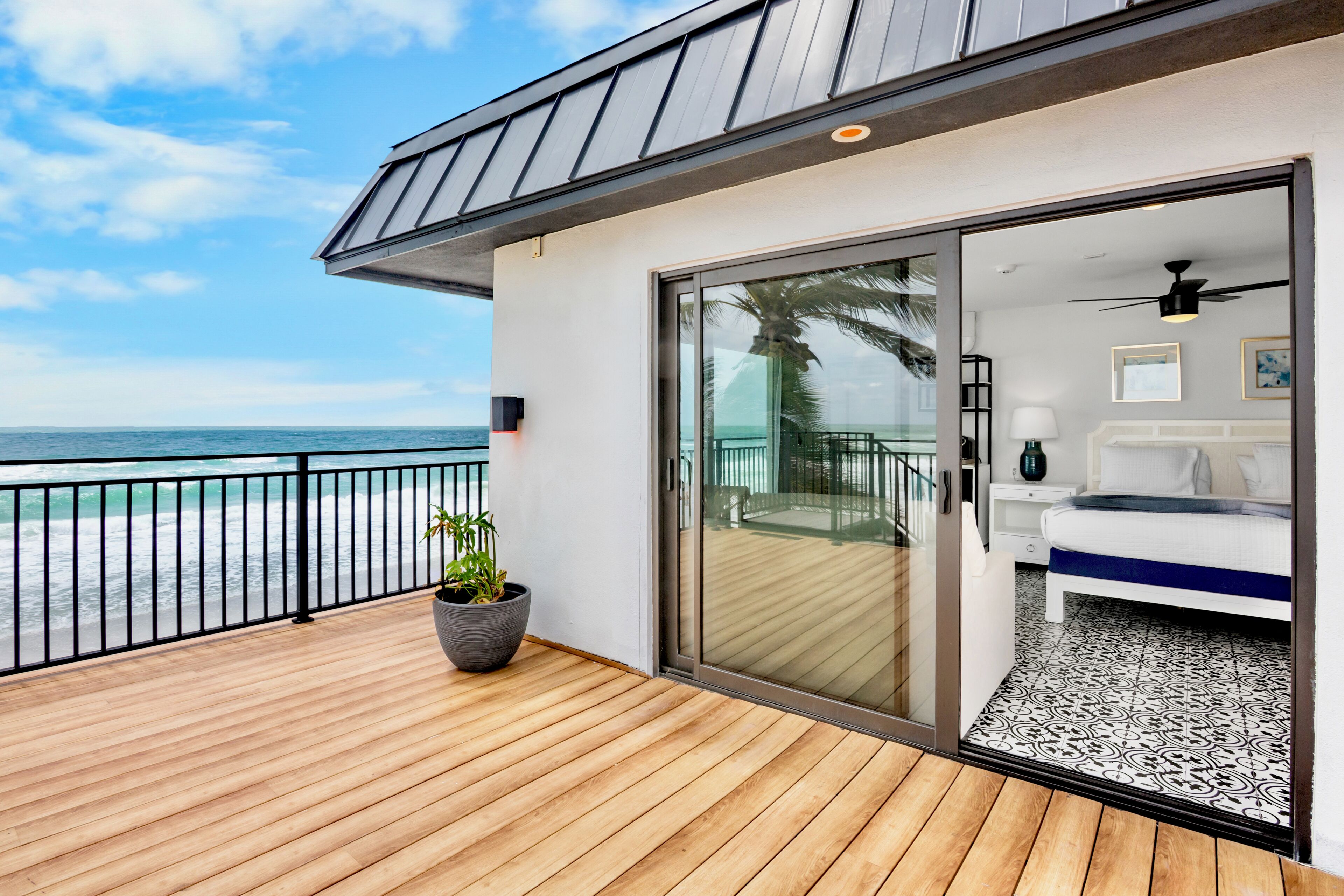 Una habitación moderna con un amplio ventanal corredizo que da a un balcón con vista al océano.