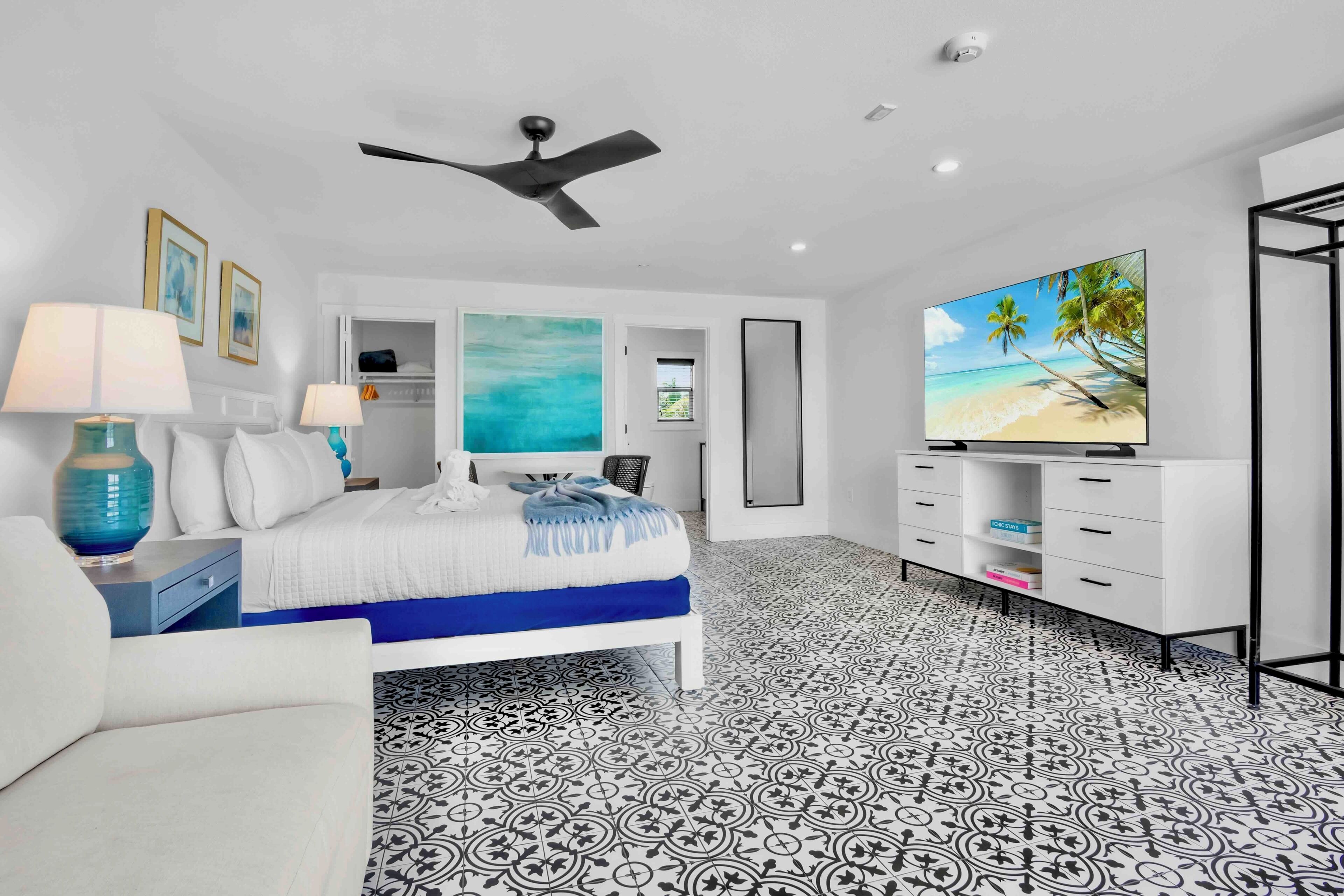 A modern bedroom with a bed, a ceiling fan, a TV, and a wardrobe.