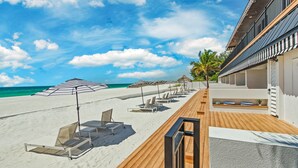 A beachside hotel with a wooden deck, lounge chairs, and umbrellas. - Seaside at Anna Maria Island Inn (Bradenton Beach)