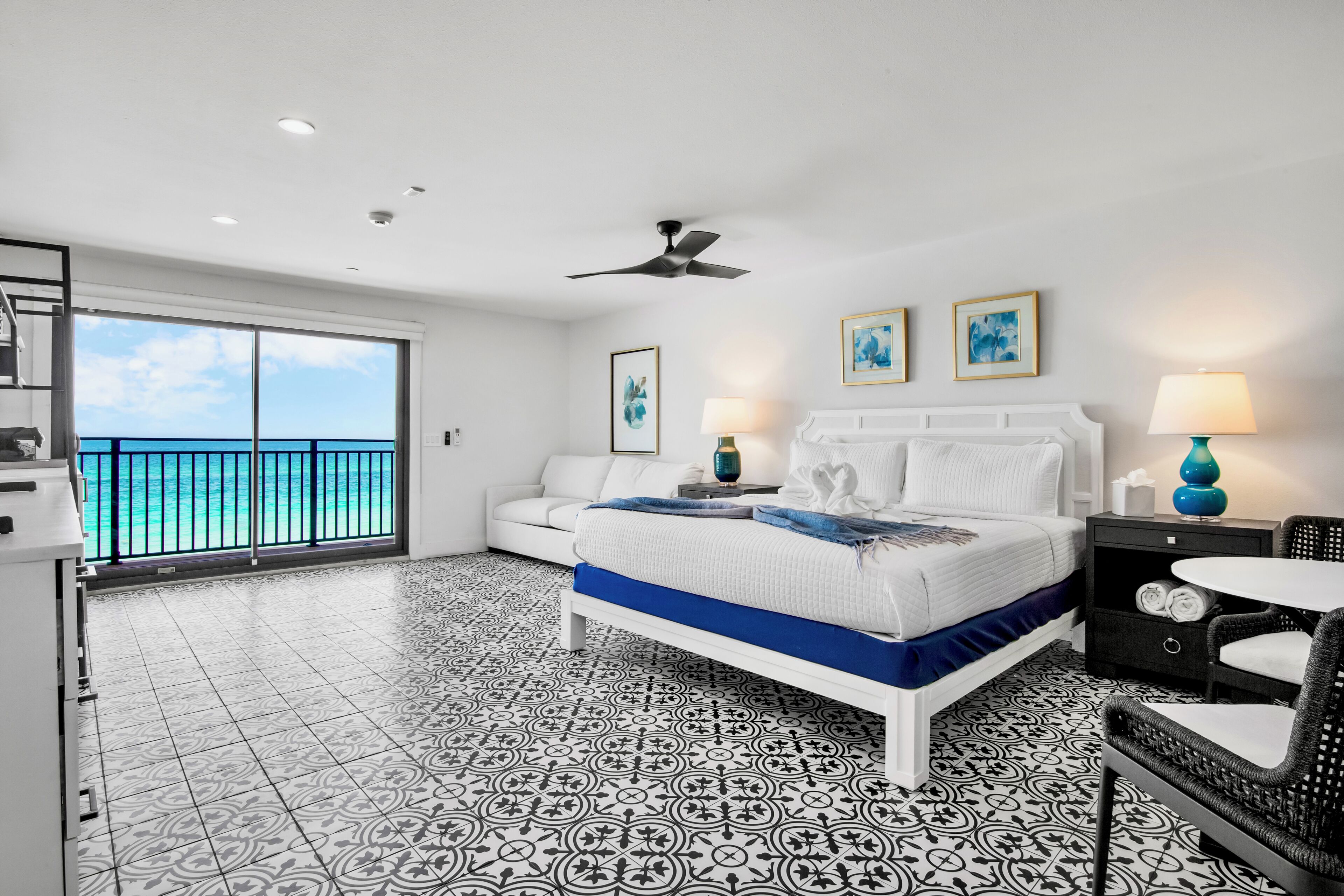 A hotel room with a balcony, a bed, a desk, and a chair.