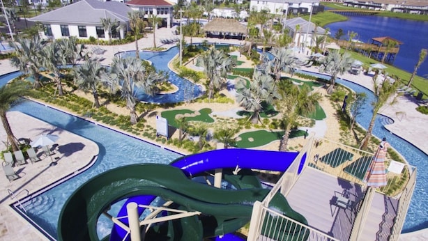 A water park with a large green water slide, multiple pools, and palm trees. - Amazing Townhome with private pool SL3054 (Kissimmee)