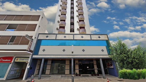 A hotel with a modern design, featuring a prominent central tower with balconies. - Hotel Vind's Plaza (Caratinga)