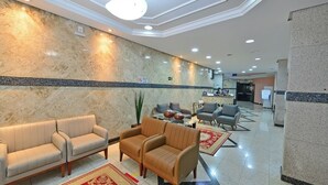 A hotel lobby with seating areas, a reception desk, and a kitchen in the background. - Hotel Vind's Plaza (Caratinga)