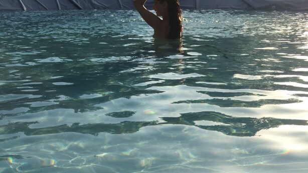 Ein klares Schwimmbecken mit sichtbaren Sandstrukturen und einer Person im Wasser.