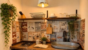 Eine Küche mit Gaskochfeld, Holzschränken, einer hängenden Pflanze und Wanddekoration im Vintage-Stil.