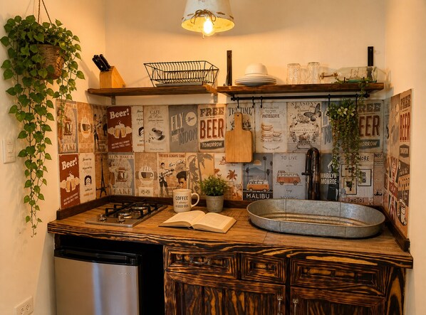 Une cuisine équipée d’une cuisinière à gaz, de meubles en bois, d’une plante suspendue et de décorations murales sur le thème du style vintage.