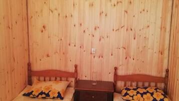 A room with wooden walls and two single beds with floral bedding.
