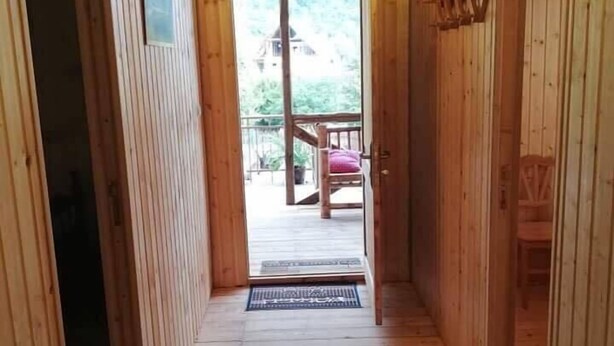 A wooden hallway leading to a balcony with a view of a house and trees. - Agro Guesthouse Korena (Tkibuli)