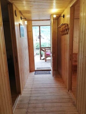 A wooden hallway leading to a balcony with a view of a house and trees. - Agro Guesthouse Korena (Tkibuli)