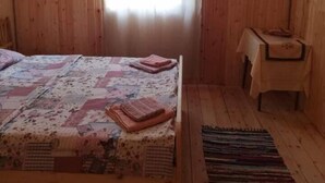 A wooden room with a bed, a small table, and a window. - Agro Guesthouse Korena (Tkibuli)