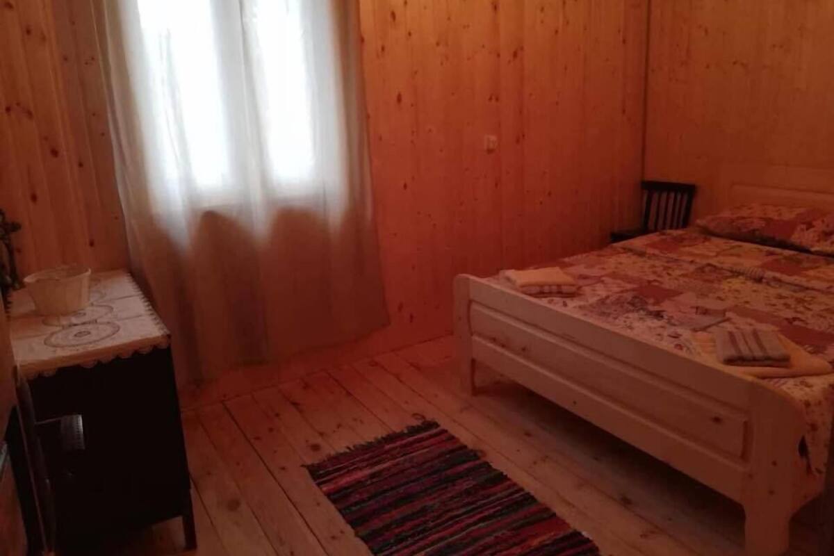 A wooden-paneled room with a bed, a small table, and a chair.