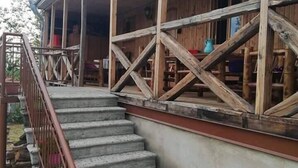 A wooden building with a covered porch and a staircase leading to an upper level. - Agro Guesthouse Korena (Tkibuli)