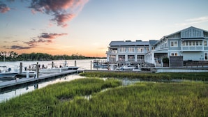 A waterfront property with a dock, boats, and a large building with multiple levels and balconies. - Beaufort Hotel NC (Beaufort)