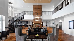 A spacious lobby with a high ceiling, a central seating area with a dark wood coffee table, and a staircase leading to an upper level. - Beaufort Hotel NC (Beaufort)