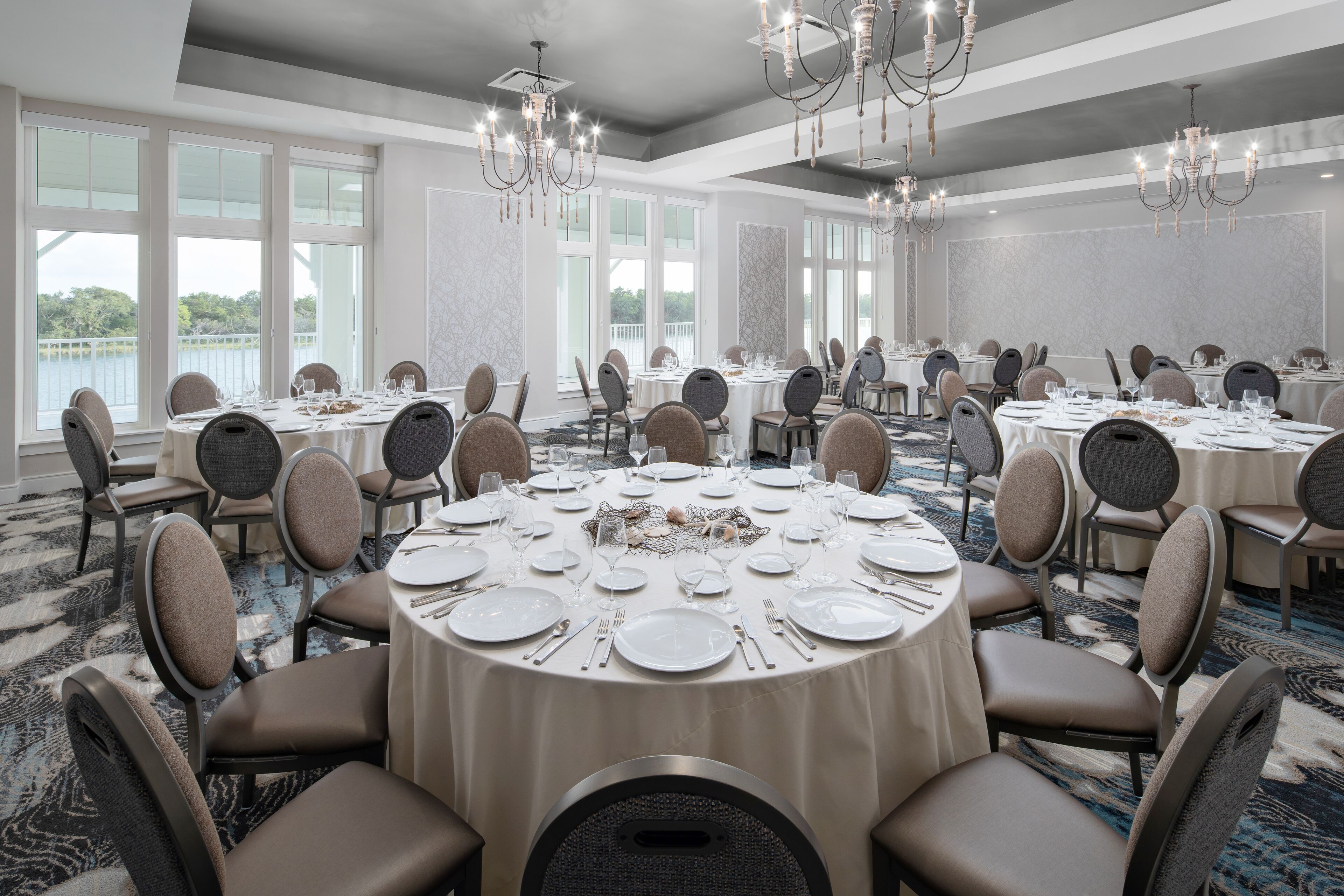 Un gran salón de banquetes con mesas redondas dispuestas para comer, equipado con sillas y vajilla.