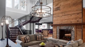 A spacious living area with a staircase, a fireplace, and a large window. - Beaufort Hotel NC (Beaufort)