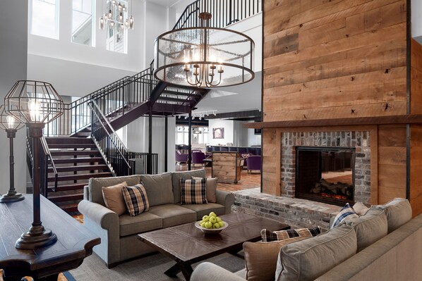 A spacious living area with a staircase, a fireplace, and a large window.