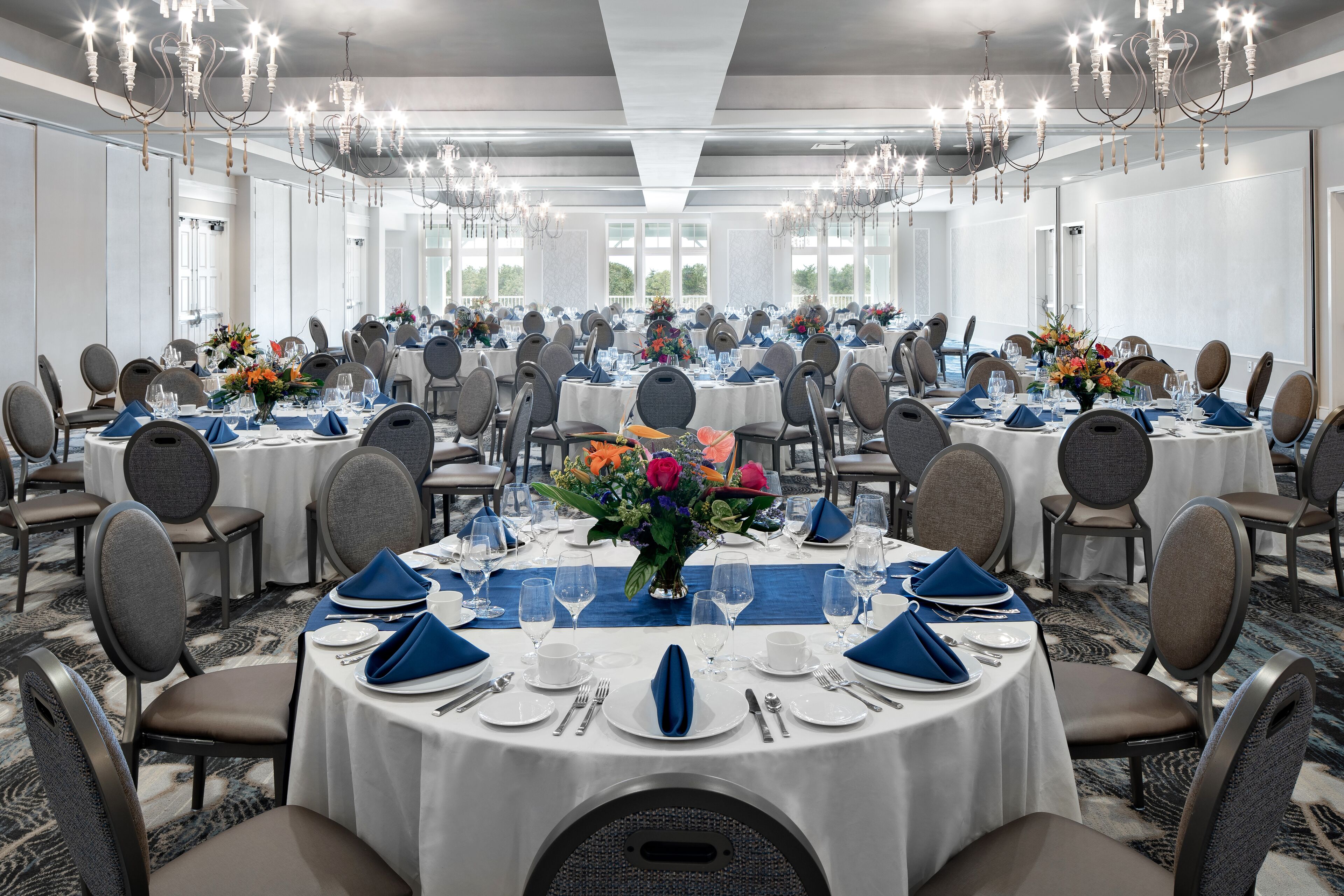 Un amplio salón de banquetes con mesas redondas, sillas y candelabros.