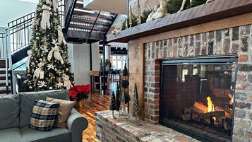Un espacio de sala acogedor con chimenea, un árbol de Navidad y una escalera.