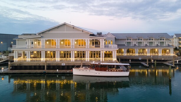A waterfront hotel with multiple levels, large windows, and a docked boat. - Beaufort Hotel NC (Beaufort)