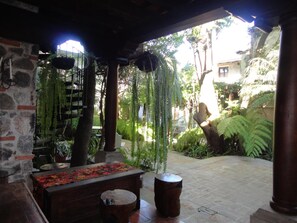 A covered outdoor area with stone walls, a wooden bench, hanging plants, and a tiled floor. - Cissus Boutique Hotel - Adults Only (Antigua Guatemala)
