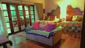 A cozy bedroom with a sofa, a bed with a quilt, and a wooden headboard.