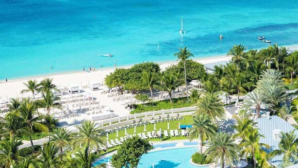 Un complexe hôtelier doté d’une piscine, d’une plage et de palmiers.