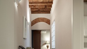Un pasillo con suelo de madera, un armario de madera, una lámpara y un cuadro en la pared.