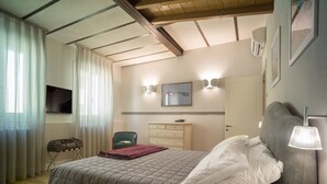 Un dormitorio con cama, una silla, cómoda, televisor de pantalla plana y lámpara de pared.