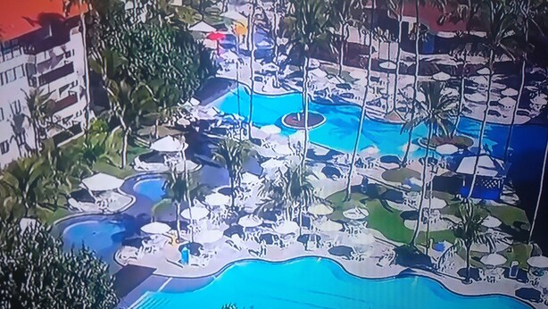 Ein Resort mit mehreren Schwimmbecken, Palmen und Liegebereichen.