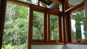 A bathroom with wooden window frames and a view of a lush garden. - Farmhouse on Félix Beach  (Ubatuba)