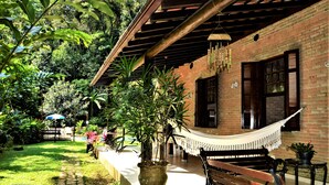 A covered patio area with a hammock, brick walls, and potted plants. - Farmhouse on Félix Beach  (Ubatuba)