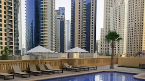 A swimming pool with lounge chairs and umbrellas, surrounded by high-rise buildings. - Pelicanstay Seaview Suites in JBR Walk (Dubai)