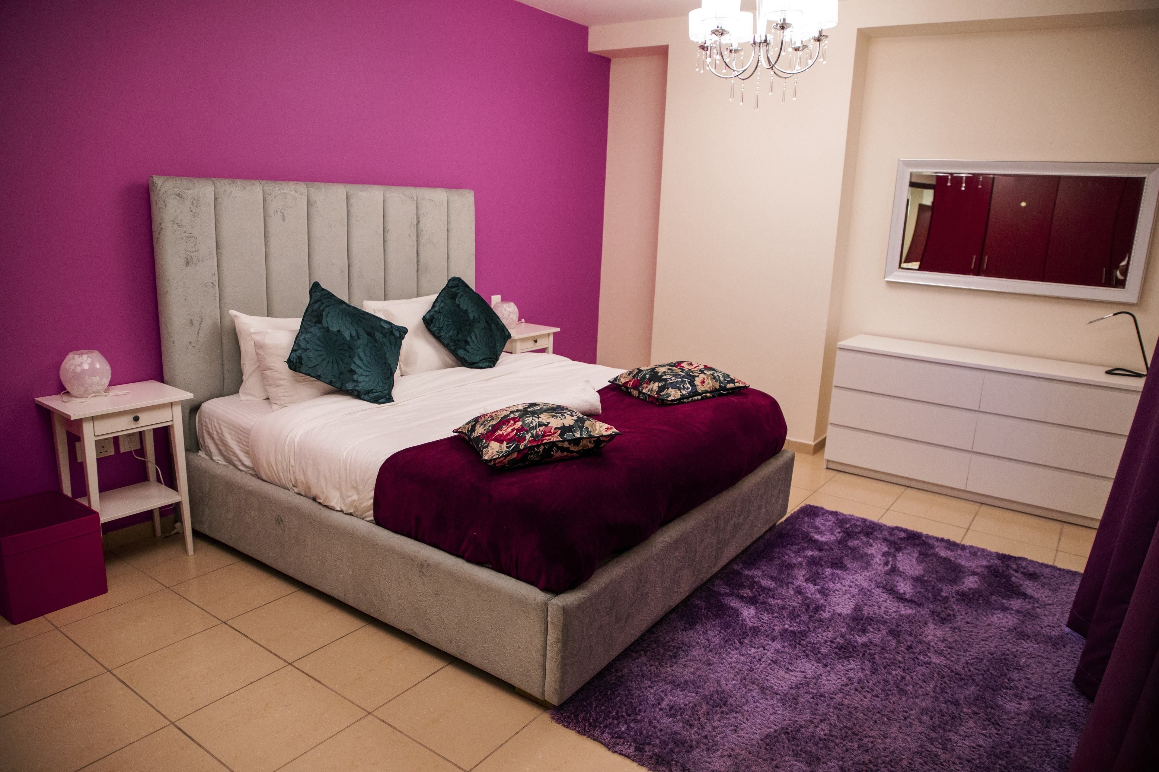 A bedroom with a bed, nightstands, a dresser, and a mirror.