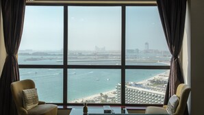 A room with a large window overlooking a body of water, a chair, and a table with a decorative item. - Pelicanstay Seaview Suites in JBR Walk (Dubai)