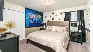 Ein Schlafzimmer mit einem großen Bett, einem Flachbildfernseher, einem Nachttisch und einer Kommode.