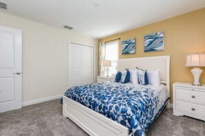 A bedroom with a bed, nightstands, a door, and artwork on the wall. - Champions Gate Exec Villas- 1605maid (Davenport)