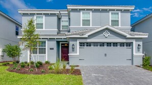 Une maison à deux étages avec une façade grise, une porte rouge et un garage.