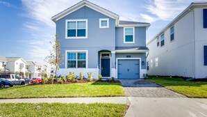 Un immeuble résidentiel à deux étages, à la façade bleue et blanche, avec un garage à l’avant et une pelouse bien entretenue.